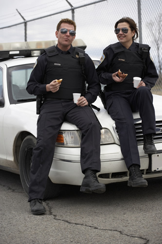 Police eating donuts on the hood of the police car 